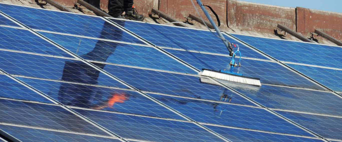 Ein Arbeiter reinigt Solarpanels auf einem Dach.