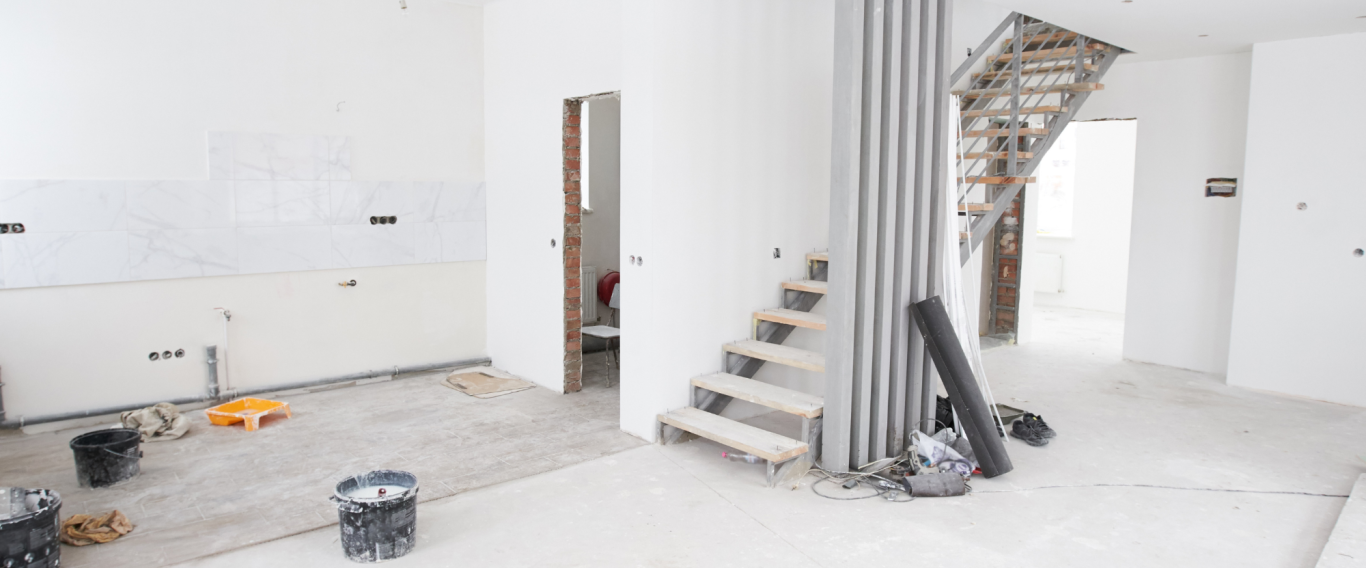 Unfertiger Innenraum mit Treppe, Bauutensilien und unvollendeten Wänden.