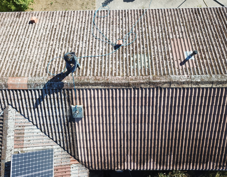 Ein Dachreiniger arbeitet auf einem Dach mit Ziegeln und Solarpanels.